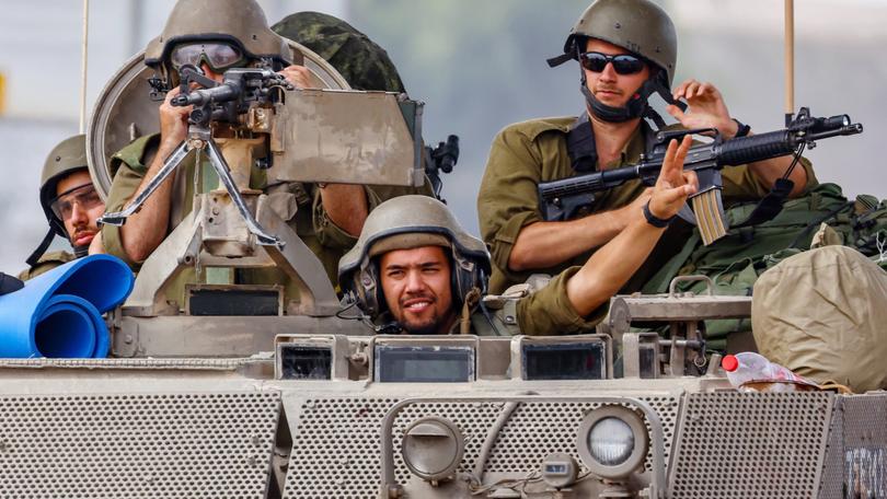 Israeli soldiers drive with an armoured personnel carrier (APC) and greet fellow soldiers on patrol near the border with Gaza, in Israel, 29 October 2023. 