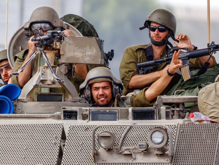 Israeli soldiers drive with an armoured personnel carrier (APC) and greet fellow soldiers on patrol near the border with Gaza, in Israel, 29 October 2023. 