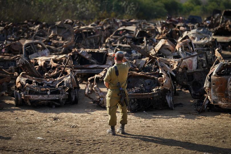 An Israeli soldier pauses for thought as he views a storage site containing hundreds of destroyed cars and vehicles that have been collected to a central point after the Hamas attacks.