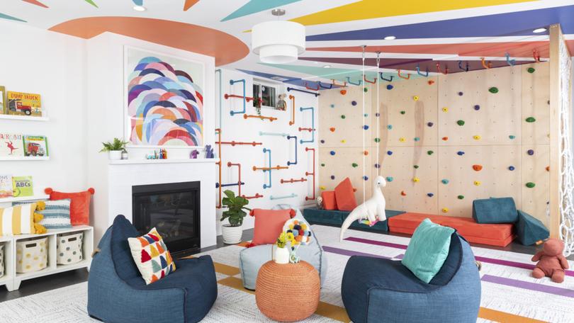 A ceiling painted with a mural and colorful monkey bars brighten up this space by grOH! Playrooms. 