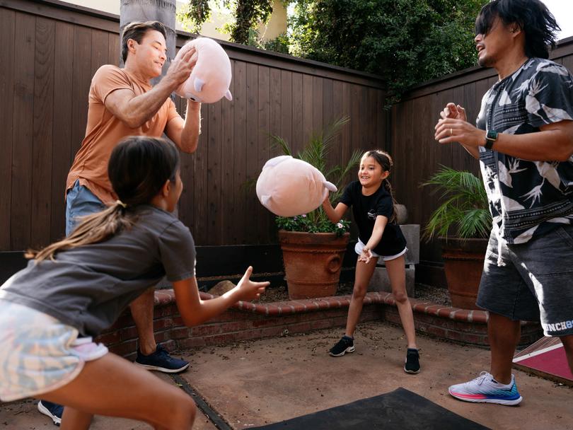 Marc Santa Maria (left), a vice president at Crunch Fitness, passes a stuffed toy with his family at their home in Los Angeles on Nov. 27, 2023. Its tough to balance child care and regular exercise, but there are ways to make real fitness gains alongside your kids. (Hana Asano/The New York Times)