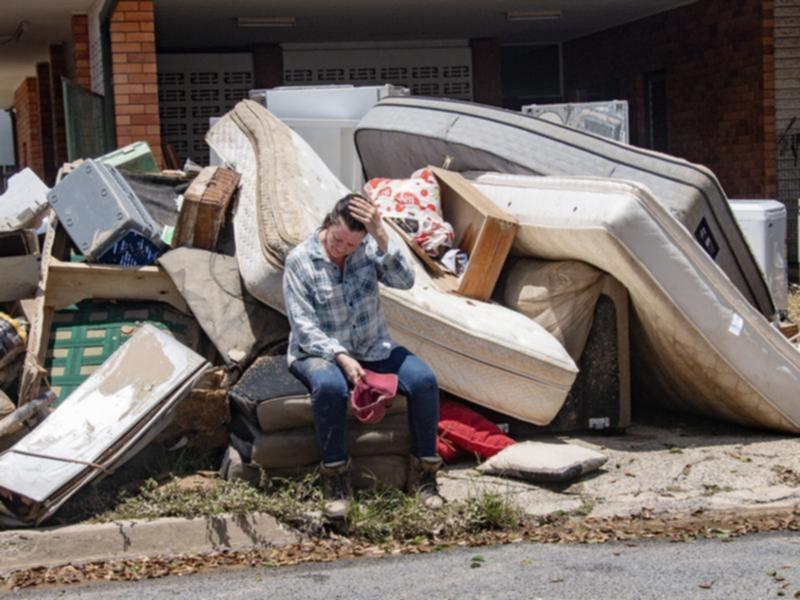 Linda Applbee sits on flood damaged furniture at her home in Cairns.