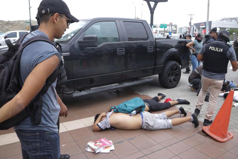 Men lie face down on the ground, detained by police after TC Television staff recognized them as part of a group of men who broke onto their set during a live broadcast, in Guayaquil, Ecuador, Tuesday, Jan. 9, 2024. The country has seen a series of attacks after the government imposed a state of emergency in the wake of the apparent escape of a powerful gang leader from prison. (AP Photo/Cesar Munoz)