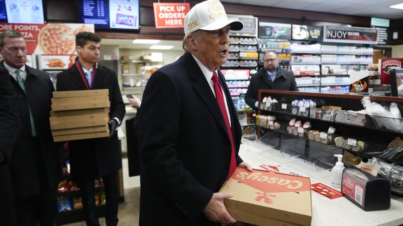 Donald Trump carries pizza at a Casey's in Waukee, Iowa, Sunday, Jan. 14, 2024. 