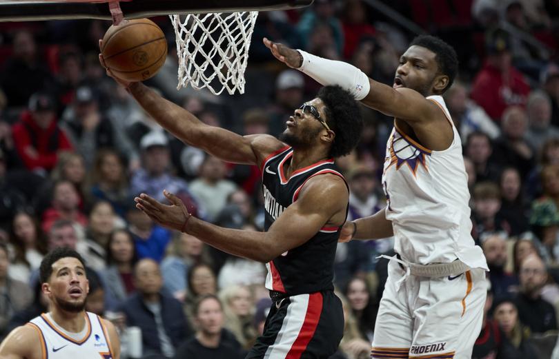 Portland Trail Blazers guard Scoot Henderson, center, looks to shoot over Phoenix Suns forward Chimezie Metu, right, during the second half of an NBA basketball game in Portland, Ore., Sunday, Jan. 14, 2024. (AP Photo/Craig Mitchelldyer)