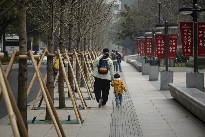 A woman and child walk along a street in Shanghai, China, Feb. 10, 2023. China’s leader, Xi Jinping, recently urged government officials’to promote a ‘marriage and childbearing culture.” 