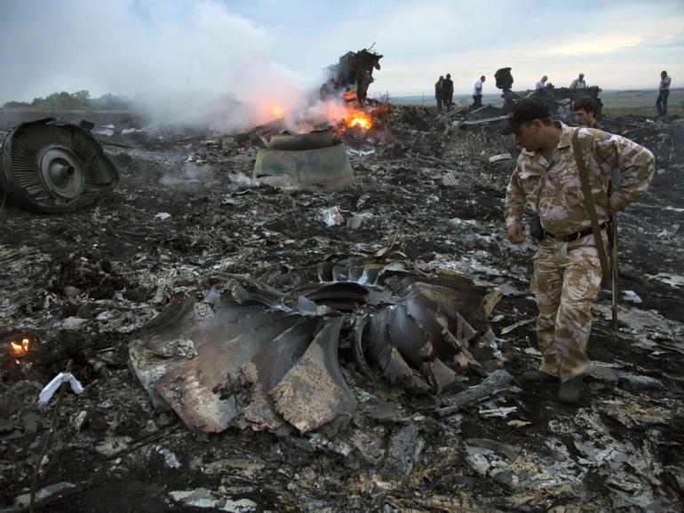 People walk amongst the debris at the crash site of MH17 in the Ukraine in 2014. (AP Photo/Dmitry Lovetsky, File)