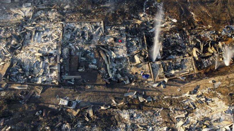 A car lies near burnt out houses and other debris after forest fires reached Vina del Mar, Chile.