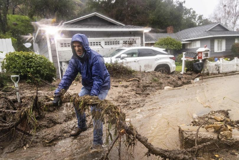 Jeffrey Raines clears debris from a mudslide at his parent's home during a rainstorm, Monday, Feb. 5, 2024, in Los Angeles. The second of back-to-back atmospheric rivers took aim at Southern California, unleashing mudslides, flooding roadways and knocking out power as the soggy state braced for another day of heavy rains. (AP Photo/Ethan Swope)