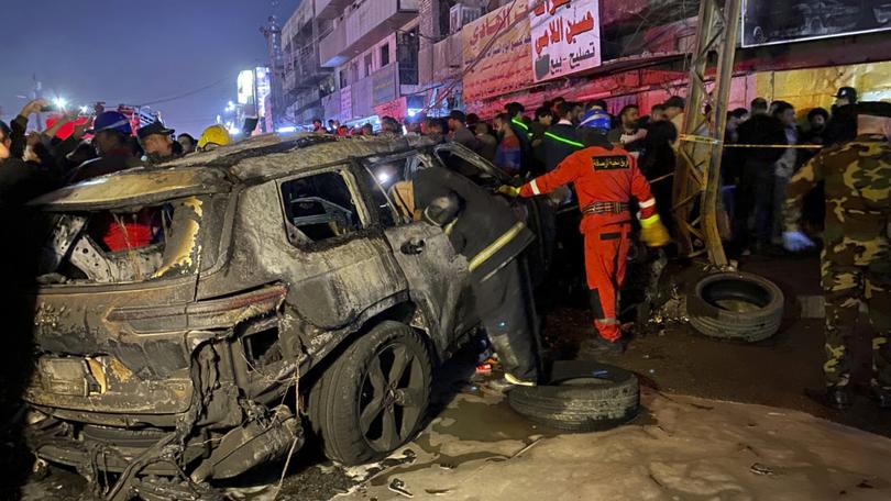 Civil defense members gather at the site of a burned vehicle targeted by a U.S. drone strike in east Baghdad, Iraq.