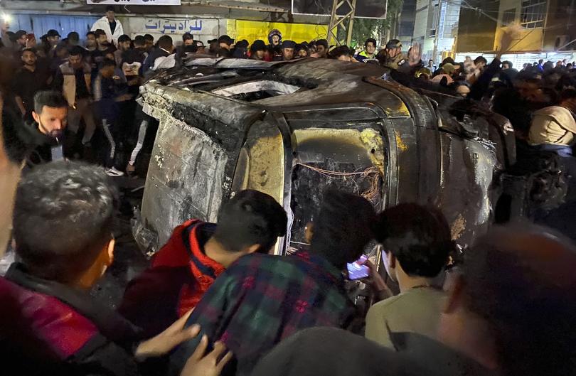 Iraqis gather at the site of a burned vehicle targeted by a U.S. drone strike in east Baghdad, Iraq, Wednesday, Feb. 7, 2024. (AP Photo/Hadi Mizban)