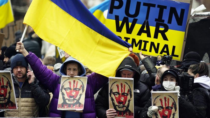 Pro-Ukraine demonstrators carry signs and Ukraine flags near Russia's UN Mission in 2022.