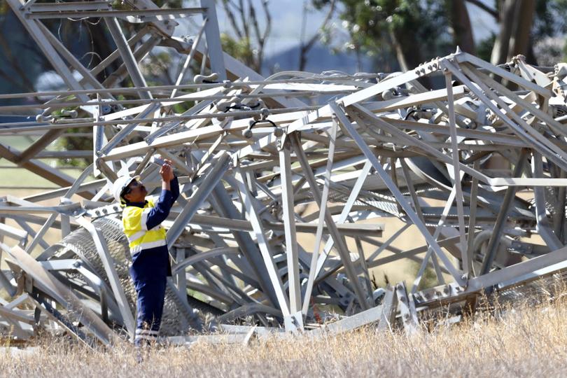 Workers are seen inspecting damaged transmission towers at Anakie.