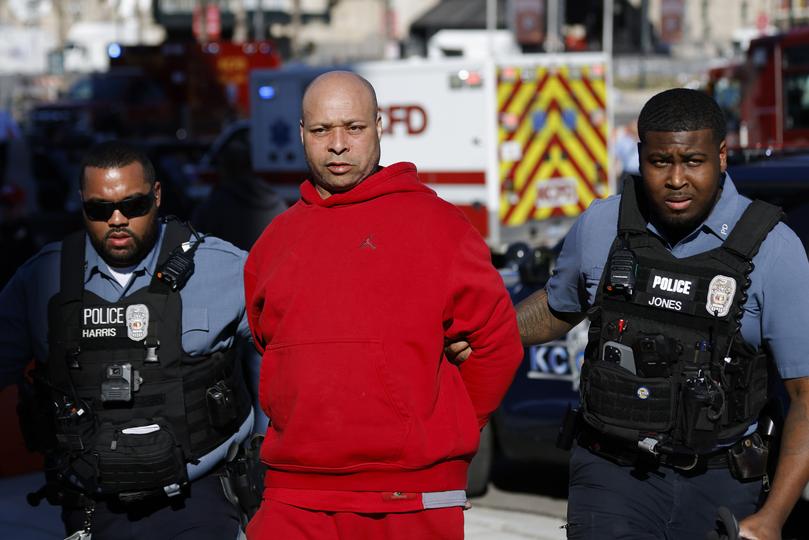 A man is detained by law enforcement following the shooting. 