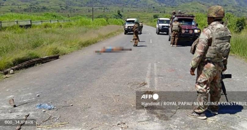 A body can be seen on a road as officials patrol near the town of Wabag, 600kms northwest of the capital Port Moresby. 