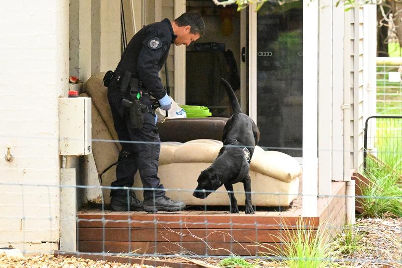 A police officer and dog at the property of Erin Patterson in Leongatha.