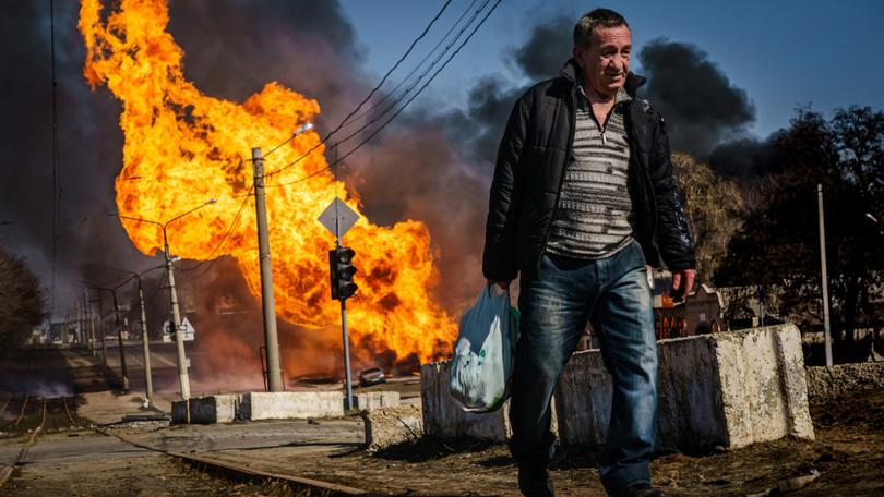 A man hurries to walk away from a building that was just hit by Russian bombardment in Kharkiv, Ukraine.