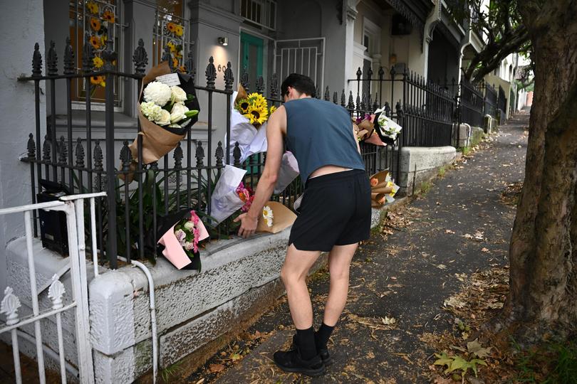 A man places flowers at the residence of Jesse Baird in Sydney.