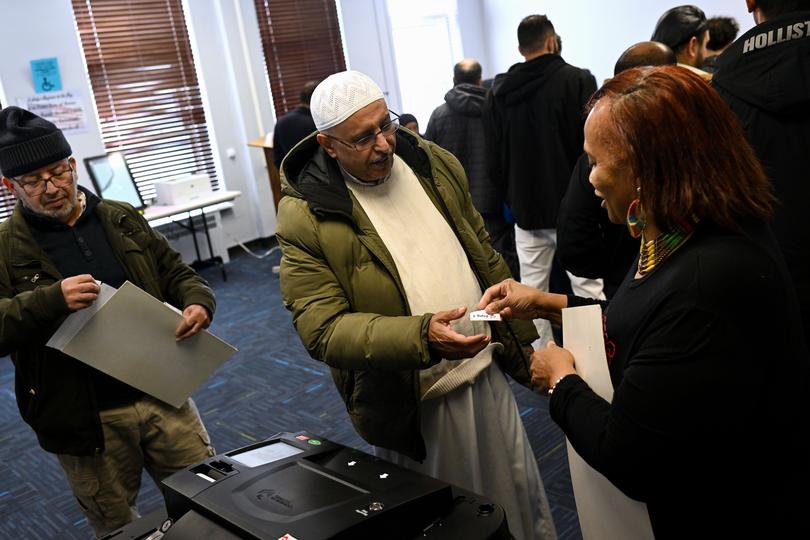 Faisel Mohamed, left, waits to cast his ballot during early voting on Sunday for the Michigan primary.