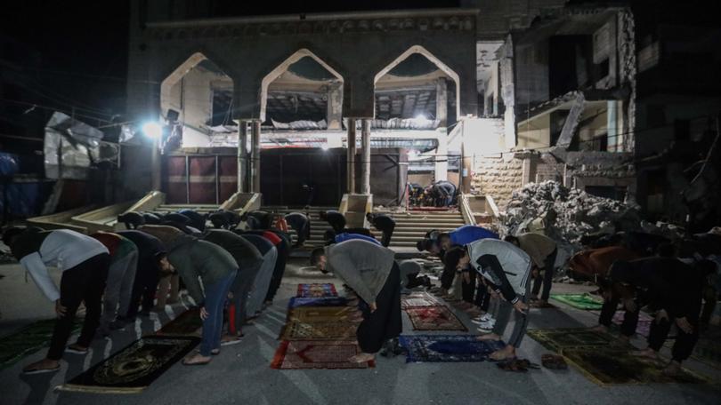 Palestinian citizens perform Tarawih prayers on the first day of the holy month of Ramadan on the rubble of Al-Huda Mosque.