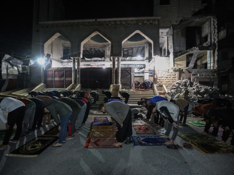 Palestinian citizens perform Tarawih prayers on the first day of the holy month of Ramadan on the rubble of Al-Huda Mosque.