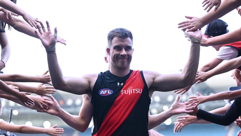 Zach Merrett of the Bombers high fives fans after winning round one. 