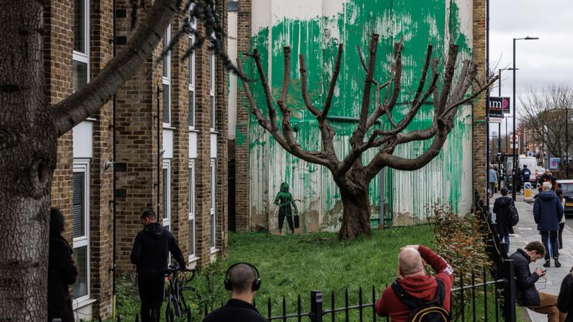 Members of the public photograph the Banksy mural which has appeared on the side of a building in Islington.