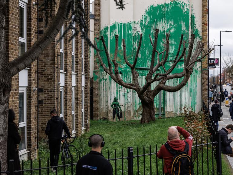 Members of the public photograph the Banksy mural which has appeared on the side of a building in Islington.