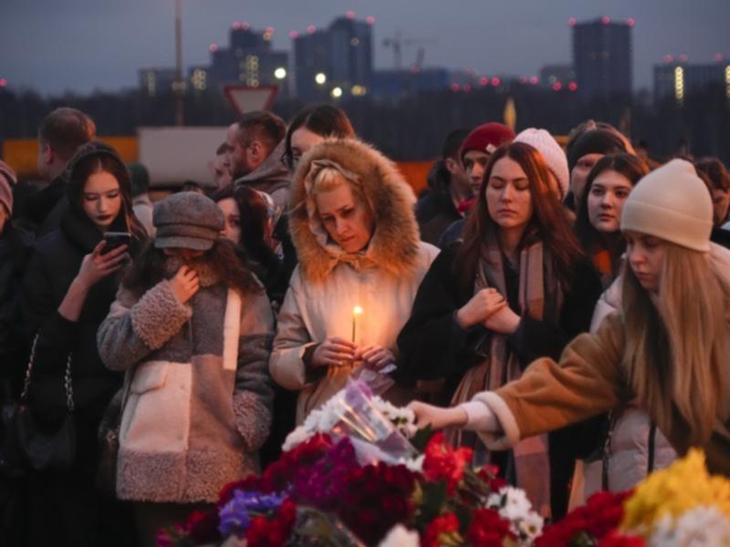 People lay flowers and light candles next to the Crocus City Hall