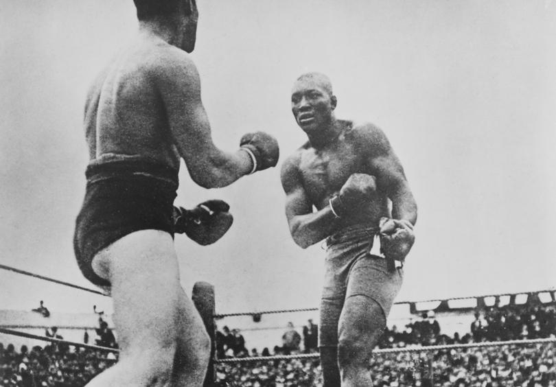 Canadian boxer Tommy Burns in action against American boxer Jack Johnson in their world heavyweight title fight at the Sydney Stadium in  1908. The fight lasted fourteen rounds before being stopped and Johnson declared the winner. 