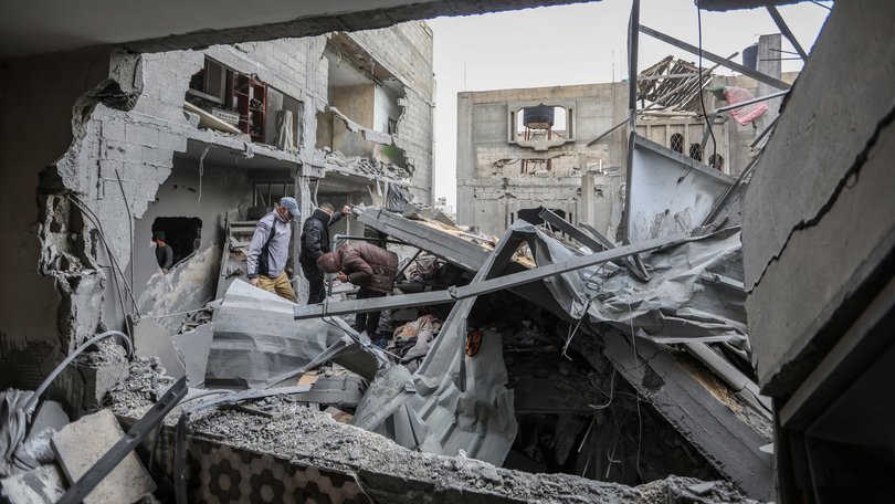 People inspect damage and recover items from their homes following Israeli air strikes.