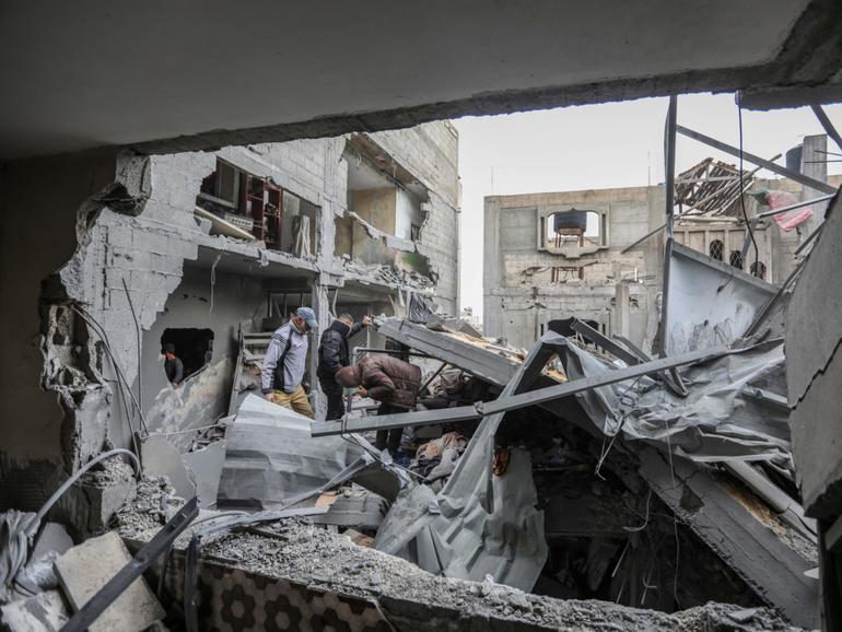 People inspect damage and recover items from their homes following Israeli air strikes.