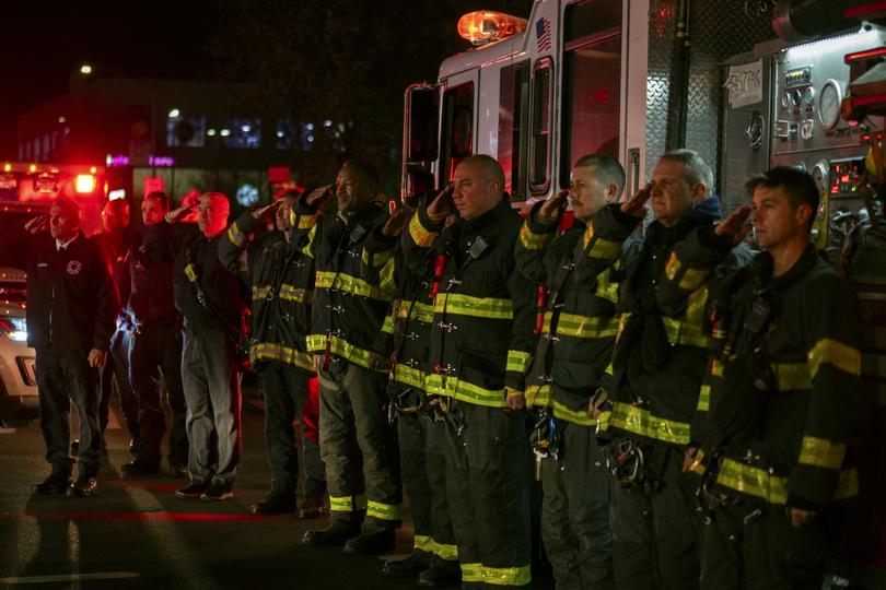 Firefighters salute as the ambulance transporting the body of New York City Police Officer Jonathan Diller.