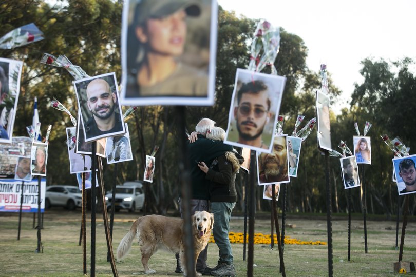 A couple hugs near photos of people who were killed during Hamas' attack on the 'Nova' festival at the site.