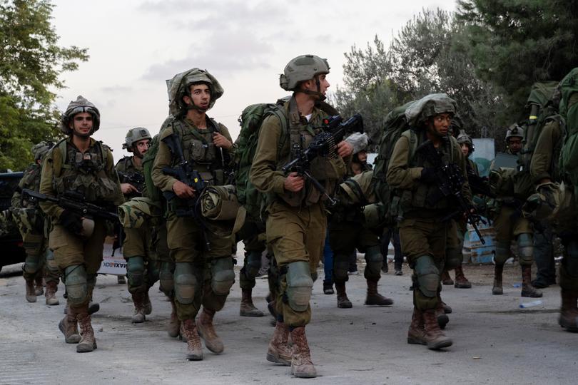 Israel Defense Forces soldiers walk through Kibbutz Be'eri where days earlier Hamas militants killed over a hundred civilians near the border with Gaza on October 11, 2023.
