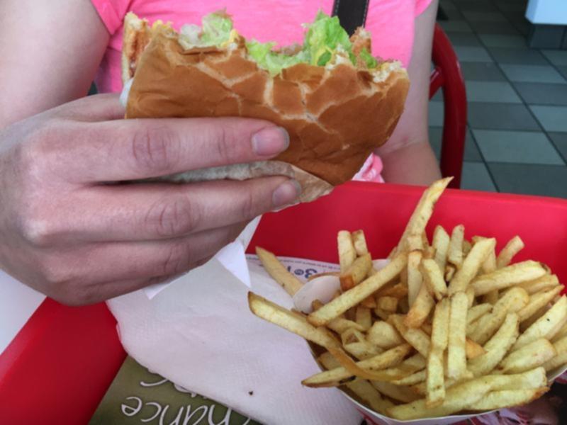 A person eating a burger and chips