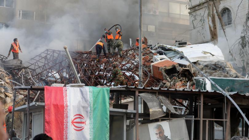 Emergency and security personnel extinguish a fire at the site of strikes on the Iranian embassy in Syria's capital of Damascus.