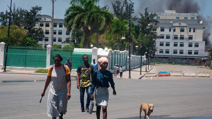People flee as smoke billows from the Ministry of Finance building behind them in Port-au-Prince. 