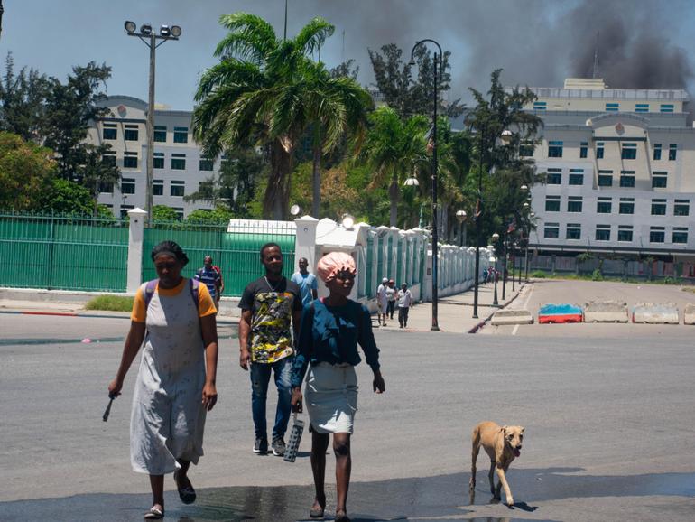 People flee as smoke billows from the Ministry of Finance building behind them in Port-au-Prince. 