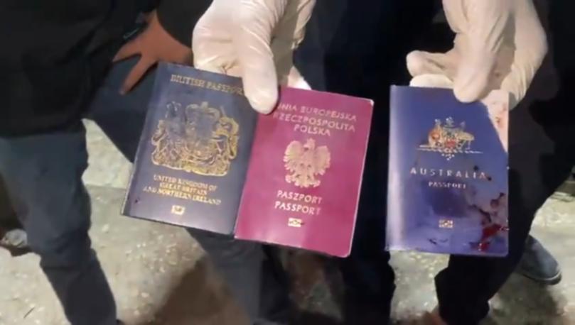 The passports of slain aid workers, including Zomi Frankcom's, are held up after the airstrike.