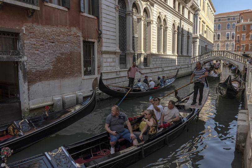 Gondola traffic on a canal in Venice, Italy, Aug. 9, 2022. Starting on April 25, 2024, tourists intending to visit the city on busy dates will be required to register on a website, and those coming for a single day will have to pay a little over $5. 