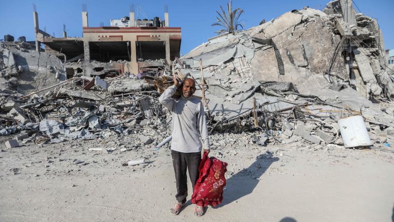 People inspect damage and remove items from their homes following Israeli airstrikes  in Khan Yunis.