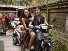Happy female friends enjoying scooter ride in alley during vacation
