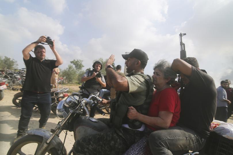 Palestinians transport a captured Israeli civilian, center, from Kfar Azza kibbutz into the Gaza Strip on Saturday, Oct. 7, 2023. The militant Hamas rulers of the Gaza Strip carried out an unprecedented, multi-front attack on Israel at daybreak Saturday, firing thousands of rockets as dozens of Hamas fighters infiltrated the heavily fortified border in several locations by air, land, and sea and catching the country off-guard on a major holiday. (AP Photo/Hatem Ali)