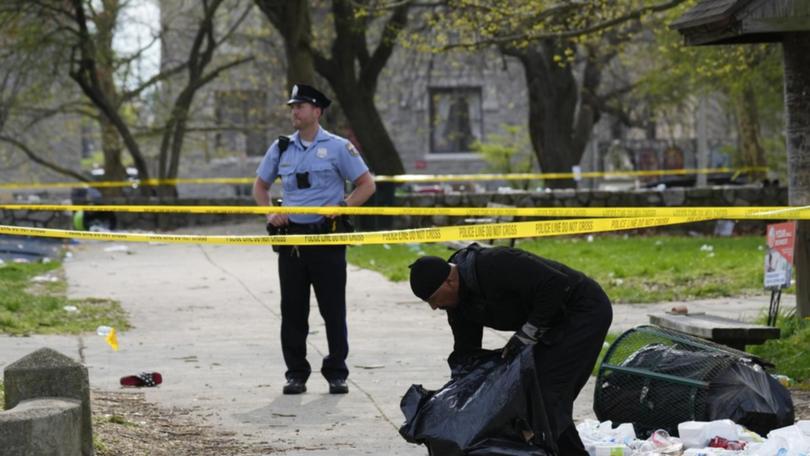A person picks up debris in the aftermath of a shooting at an Eid event in Philadelphia.