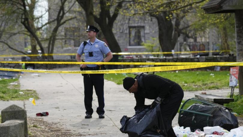 A person picks up debris in the aftermath of a shooting at an Eid event in Philadelphia. 