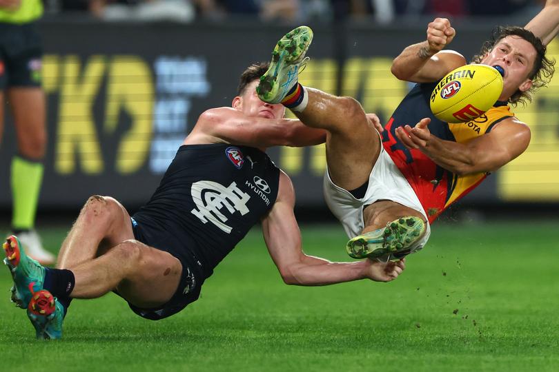 MELBOURNE, AUSTRALIA - APRIL 13: Jake Soligo of the Crows handballs whilst being tackled by Sam Walsh of the Blues during the round five AFL match between Carlton Blues and Adelaide Crows at Marvel Stadium, on April 13, 2024, in Melbourne, Australia. (Photo by Quinn Rooney/Getty Images)