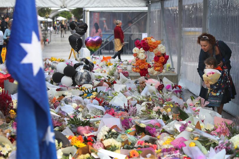 Members of the public lay flower tributes at the edge of Westfield Bondi Junction during a day of reflection on April 18, 2024 in Bondi Junction, Australia. 
