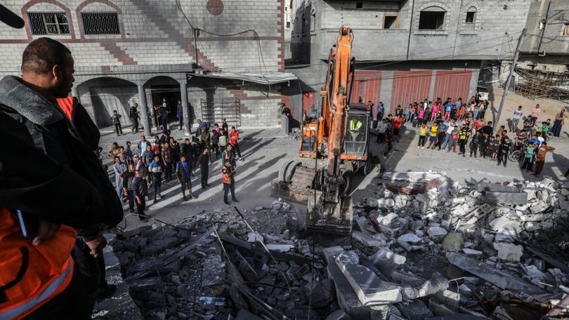 Civil defence teams and locals carry out search and rescue efforts after an Israeli attack hits a building in Rafah.