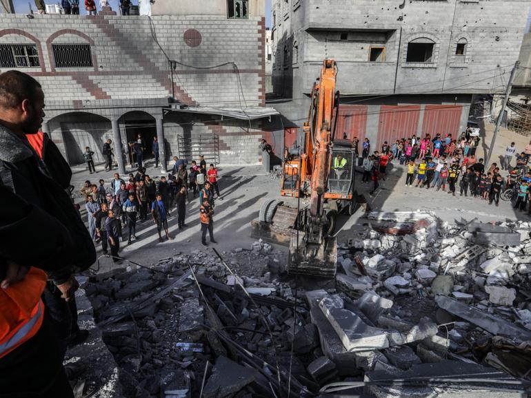 Civil defence teams and locals carry out search and rescue efforts after an Israeli attack hits a building in Rafah.